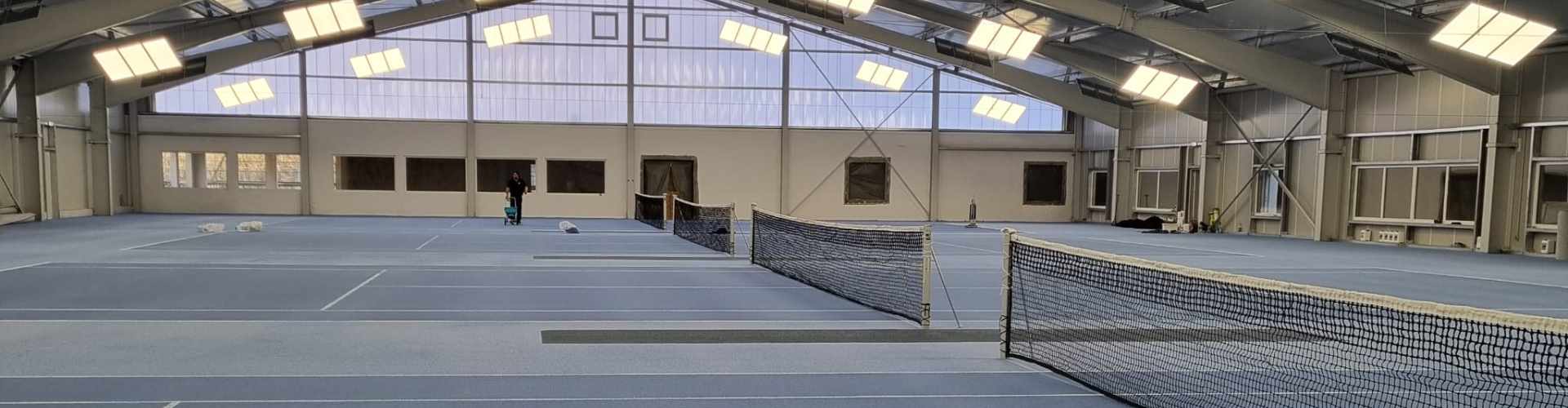 Panoramaansicht der neuen Tennishalle mit Netzen, Hightech Teppichbelag und moderner Beleuchtung