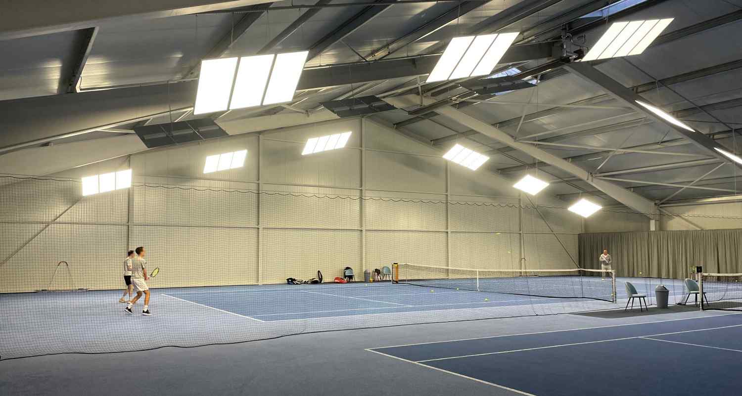 Ansicht der Tennishalle mit Tennisspielern und Tennistrainer