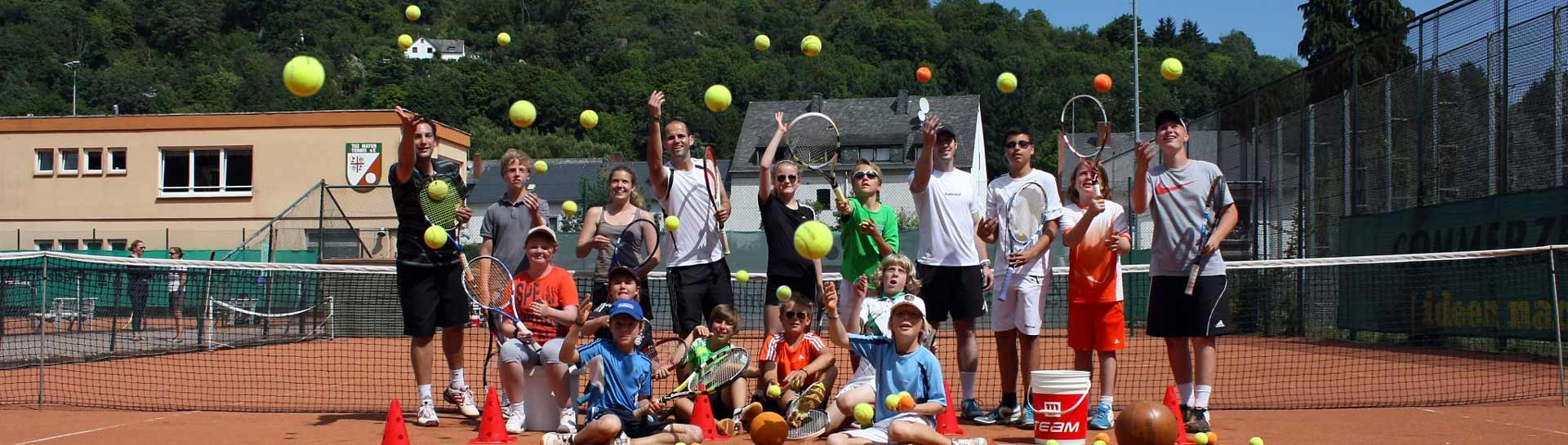 Fröhliche Kinder und Jugendliche auf einem Tennisplatz werfen Tennisbälle