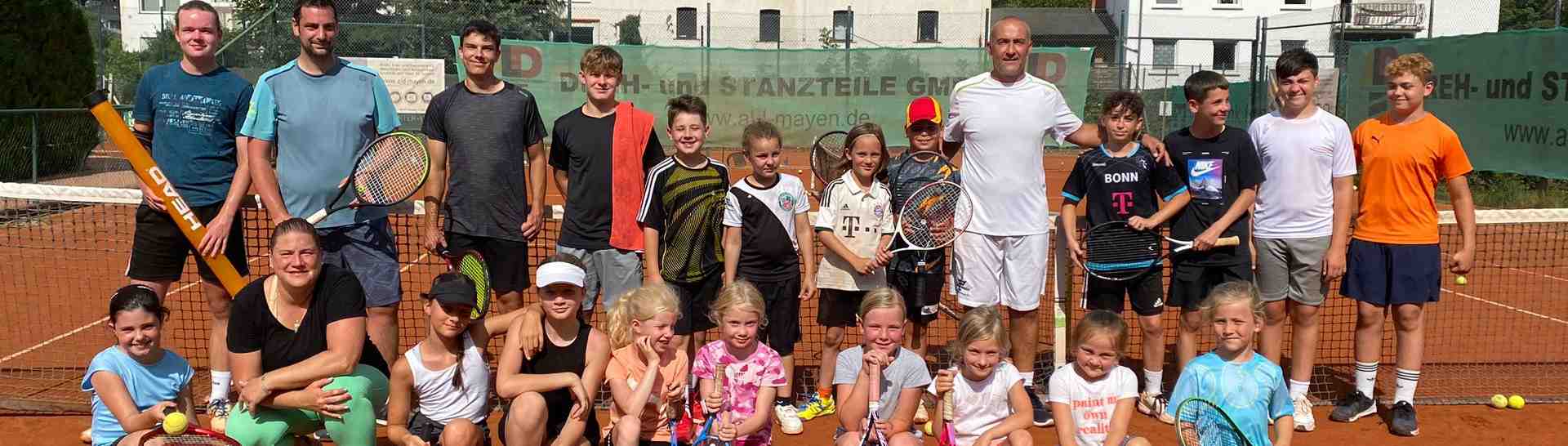 Fröhliche Kinder und Jugendliche auf einem Tennisplatz werfen Tennisbälle